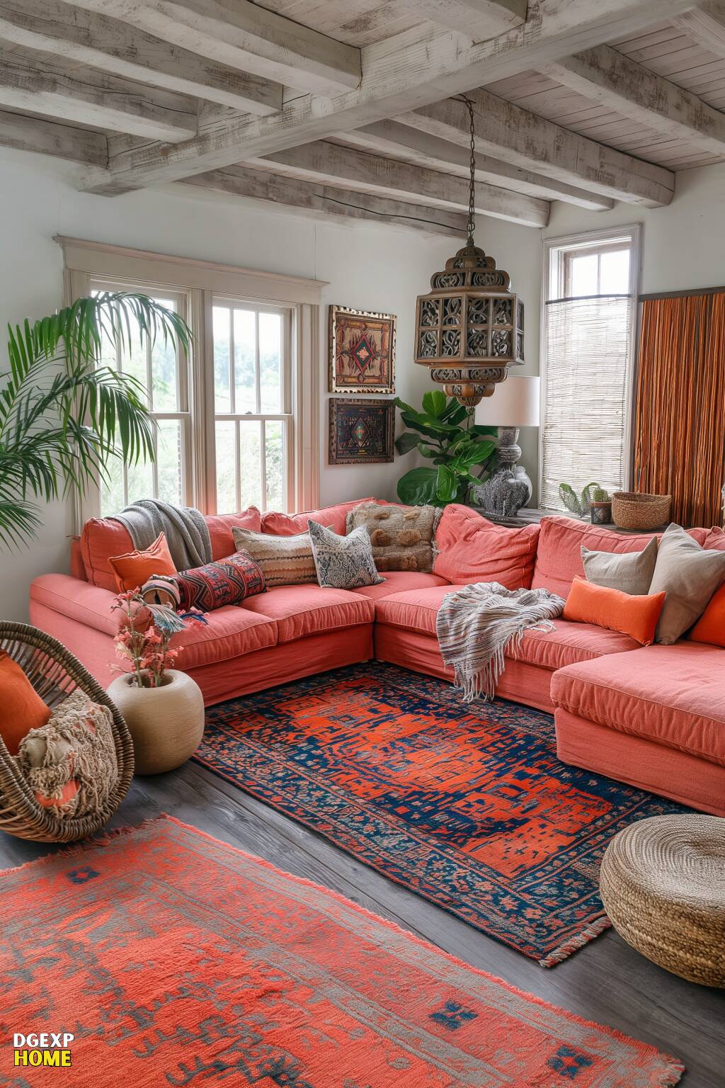 Ein Boho-Wohnzimmer mit korallenroten Sofas, leuchtend roten und blauen Teppichen und freiliegenden Holzbalken, gefüllt mit natürlichem Licht und Grünpflanzen